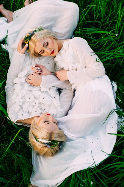 two sisters twins lying on green grass