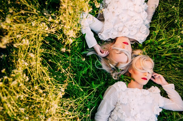 two sisters twins lying on green grass