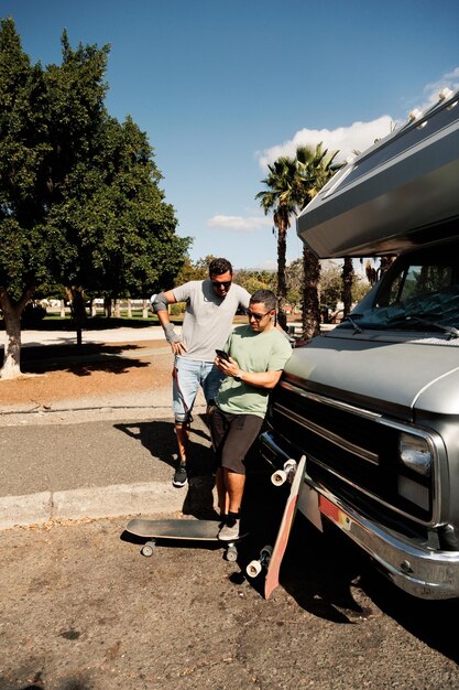 Foto due amici skateboarder che chiacchierano vicino al loro camper a gran ganaria