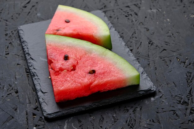 Two slices red and ripe watermelon on slate