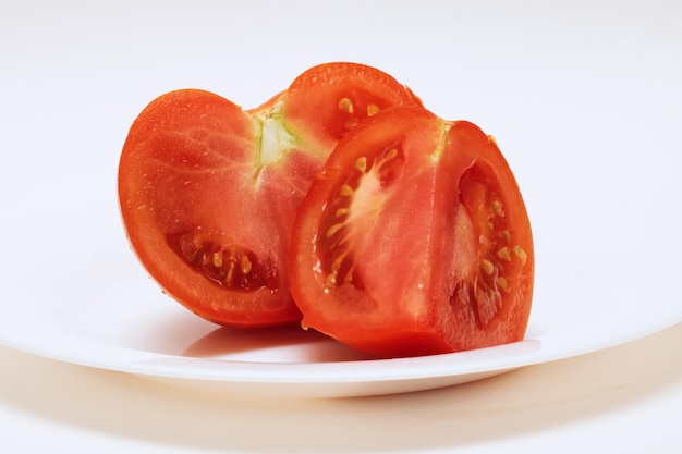 Two slices of red tomatoes on a white plate