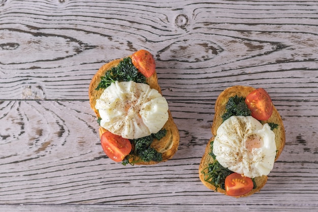 Two slices of toasted bread with poached eggs on a wooden table. Vegetarian snack with poached eggs. The view from the top.