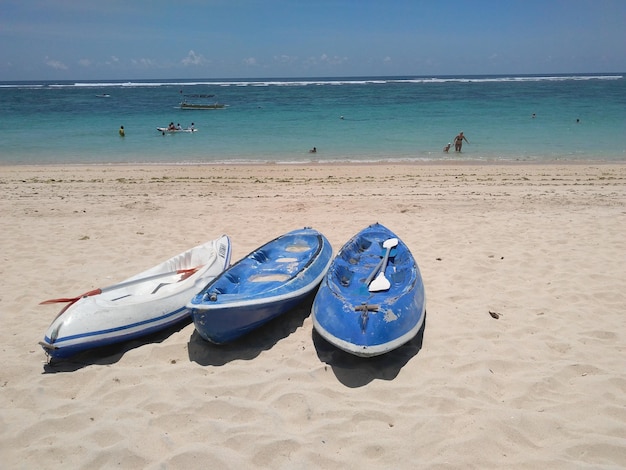 Two small boats on the beach with the ocean in the background.