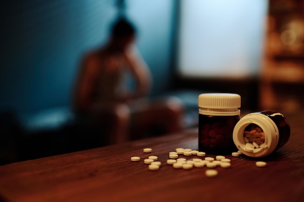 Two small bottle with painkillers or sleeping pills on wooden\
table against man