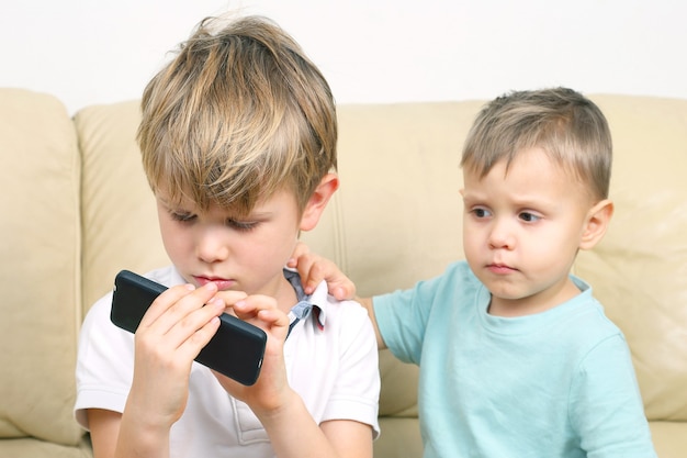 Two small boys looking at cell phone. the relations between children and modern gadgets