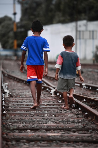 Two small children walking on the train tracks
