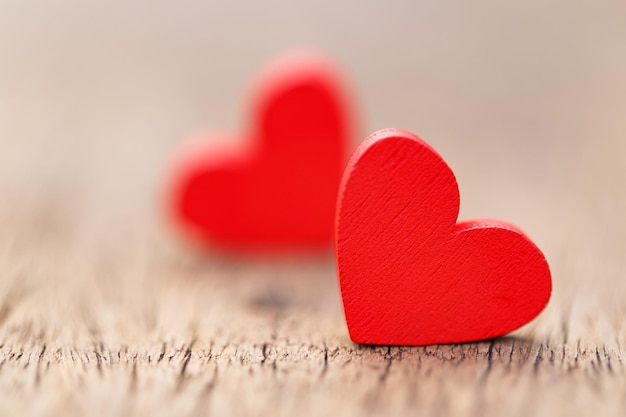 Two small red hearts made of wooden on bright white lights bokeh background Valentine day background