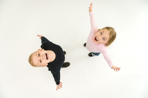 The two smile children stand on the white background. View from above