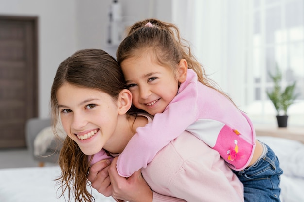 Photo two smiley little sisters together at home