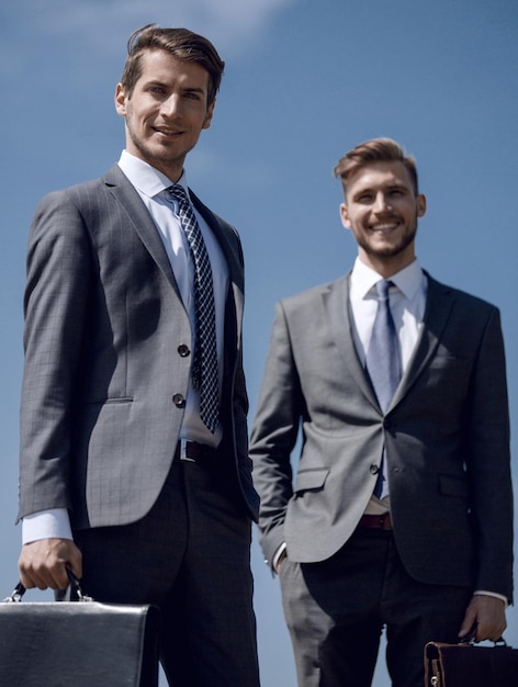 Photo two smiling business men with leather briefcasesconcept of cooperation