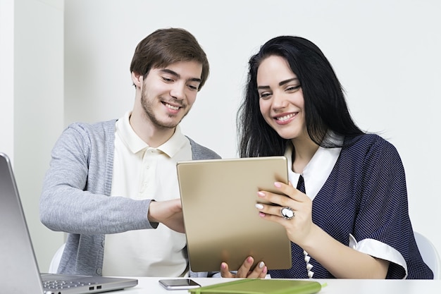 Due designer casual sorridenti che lavorano con laptop e tablet in ufficio. lavoro di squadra uomo donna.