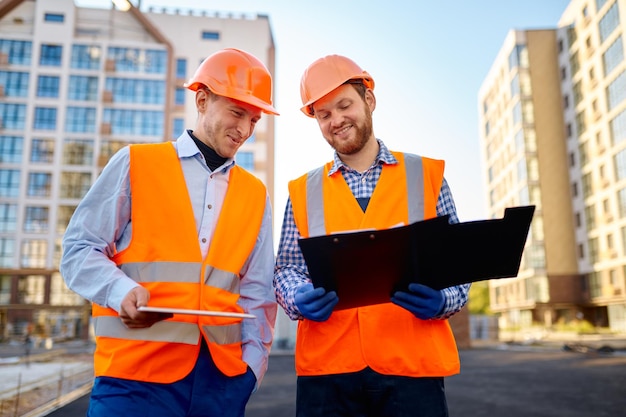 Two smiling construction workers discussing floor plan