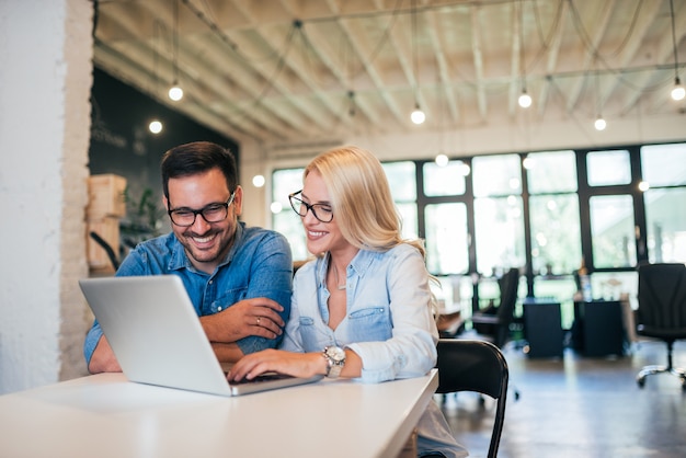 Two smiling coworkers working in a modern office.