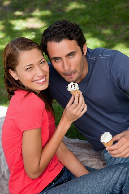 Two smiling friends looking upwards while holding ice cream