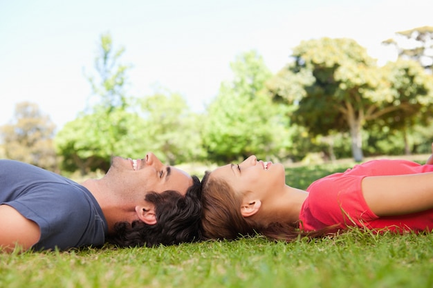 Two smiling friends looking upwards while lying head to head