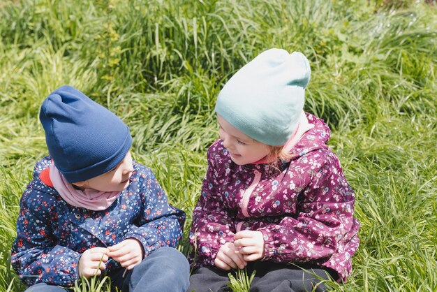 two smiling girls sit on the grass and chat  the concept of friendship and sincere feelings