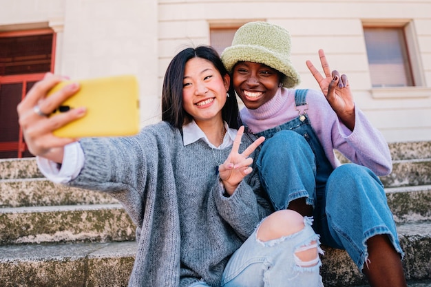 屋外でスマートフォンで自分撮りをしている2人の笑顔の女の子