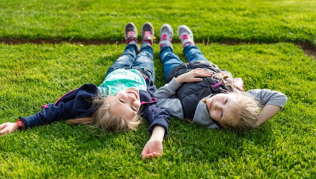 Two smiling kids lying on the grass.