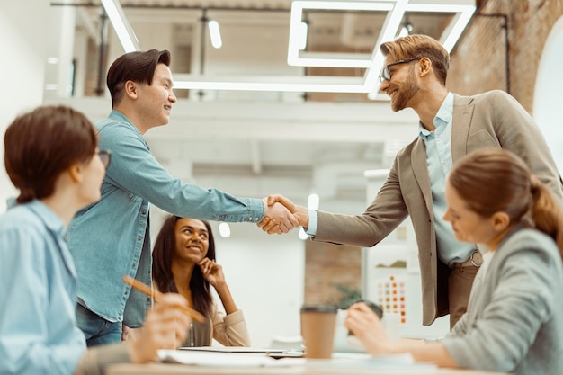 Two smiling men handshake in the office