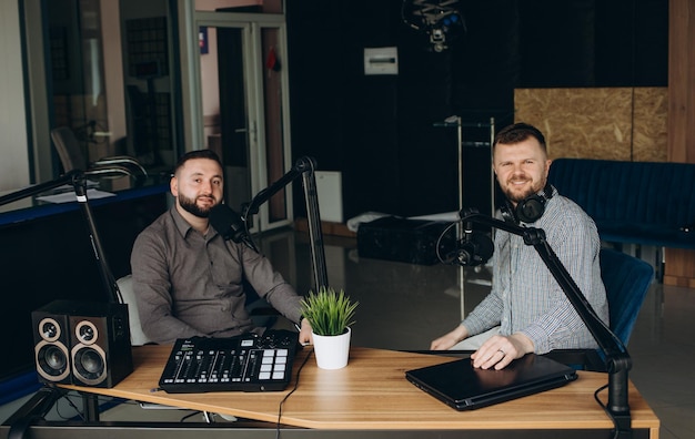 Two smiling radio hosts talking while recording podcast in broadcasting studio