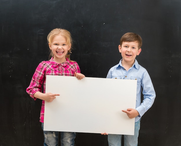 Two smiling schoolchildren with blank sheet of paper