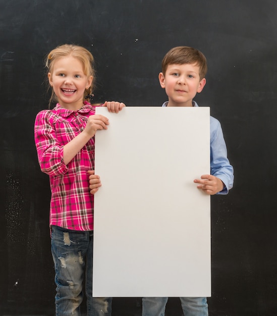 Two smiling schoolchildren with blank sheet of paper