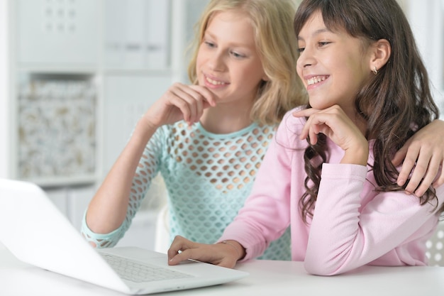 Two smiling teenage girls pointing at modern laptop