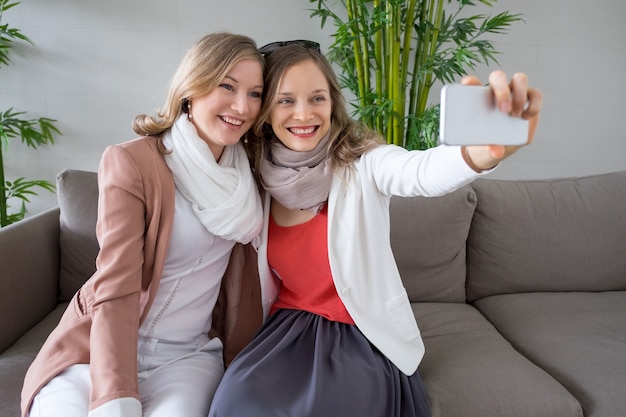 Photo two smiling women taking selfie photo in lobby