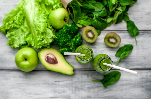 two smoothie with vegetables, avocado, apple, kiwi on a wooden background. sports nutrition