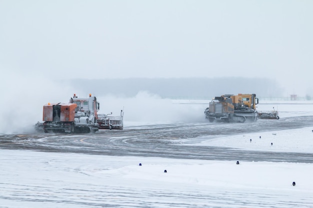 Due spazzaneve puliscono la pista di rullaggio dell'aeroporto in una bufera di neve