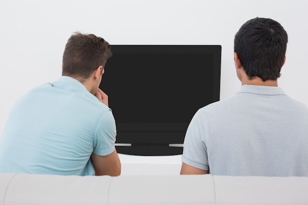 Two soccer fans watching tv