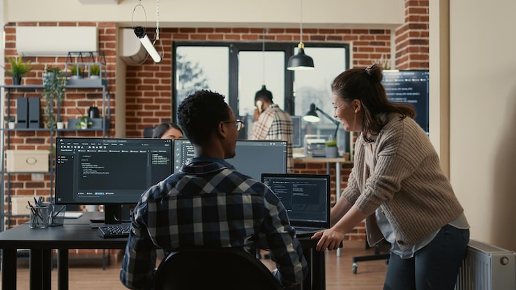 Photo two software developers doing high five hand gesture at desk with multiple screens running ai code celebrating successful algorithm. programmers colleagues enjoying teamwork results in it agency.