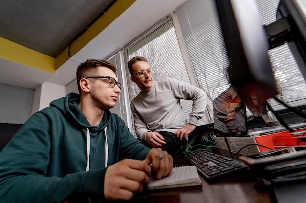 two software engineers looking attentively at the computer screen while working on project and programming in company. website design and brainstorming concept