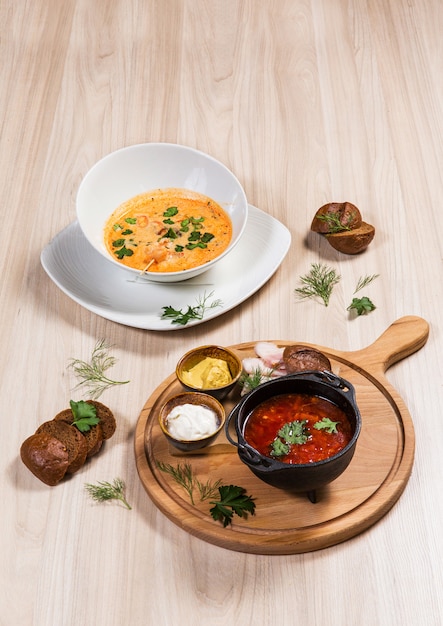 Two soups in white and black bowls on wooden table in a restaurant. Ingredients on wooden 