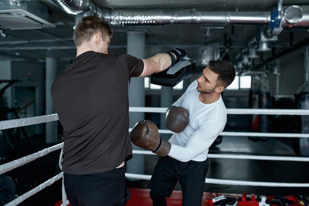 Photo two sparring partners in boxing gloves practice kicks