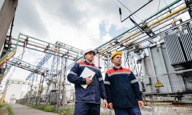 Two specialist electrical substation engineers inspect modern high-voltage equipment. Energy. Industry.