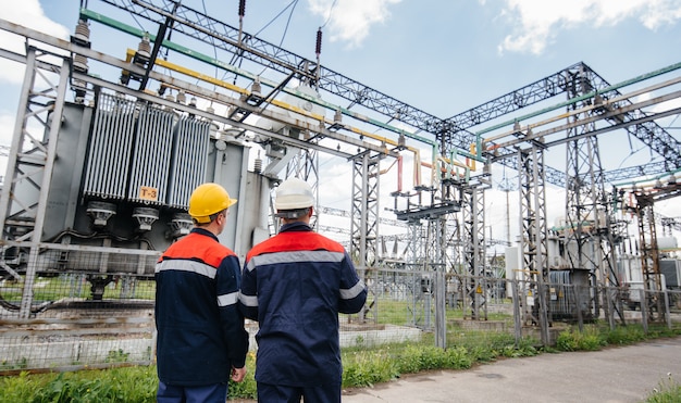 Two specialist electrical substation engineers inspect modern high-voltage equipment. Energy. Industry.