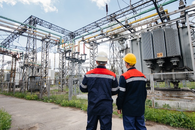 Two specialist electrical substation engineers inspect modern high-voltage equipment. Energy. Industry.