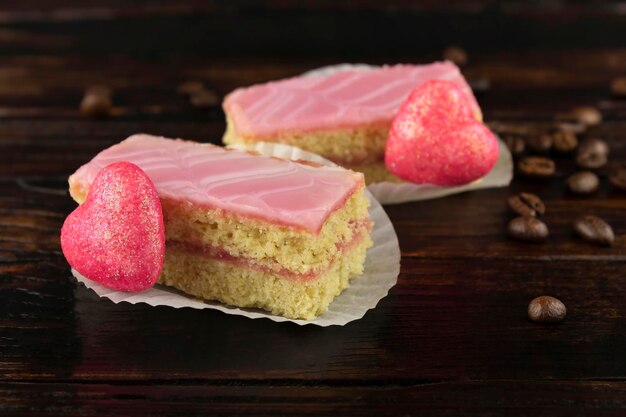 커피 콩 클로즈업이 흩어져 있는 분홍색 유약의 스폰지 케이크 2개