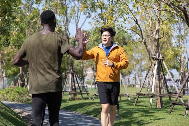 秋の朝、公園でジョギングとランニングをしている2人のスポーツ選手の黒人男性とアジア人男性。