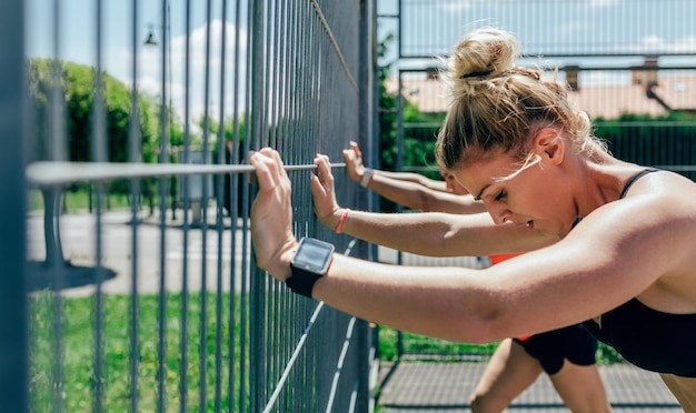 Two sportswomen supported on a fence