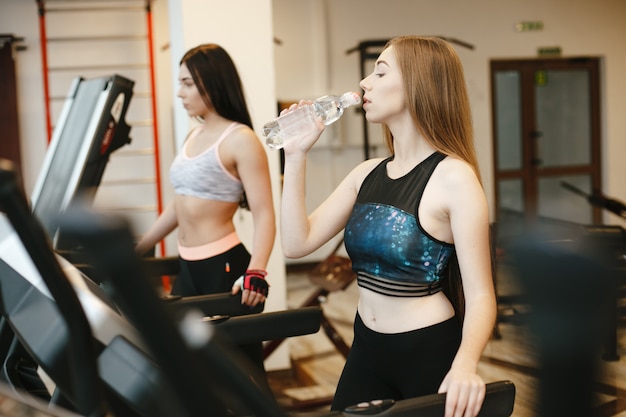 two sporty and beautiful long-haired girls train in the gym