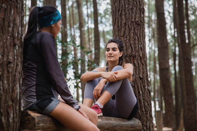 Two sporty woman rest sitting on the down trees