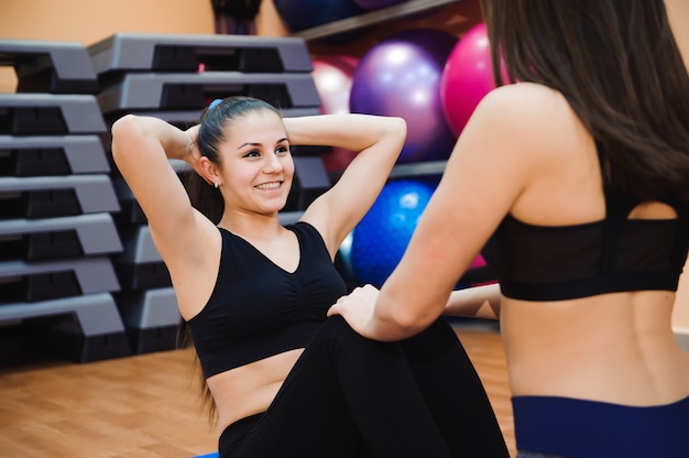 Two sporty women doing exercise abdominal crunches.