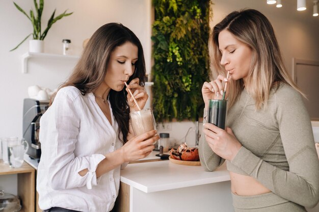 Two sportylooking girls with cocktails in their hands discuss healthy eating and diet