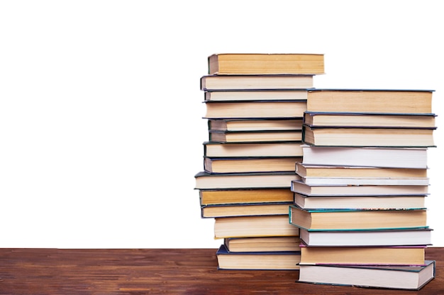 Two stacks of books on a wooden table isolated on a white background