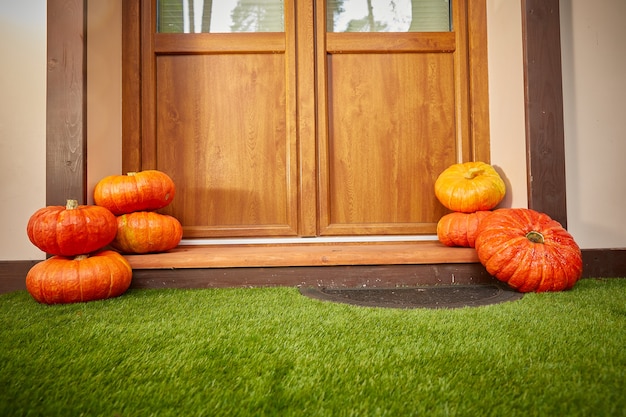 Two stacks of large orange pumpkins At the door of the house. Autumn harvest and home decor for Halloween. Copy space.