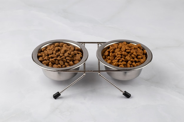 Two steel bowl of pelleted cat food. Dog bowl with animal feed for dogs. Dry dog food. A cup of kibbles for pets.