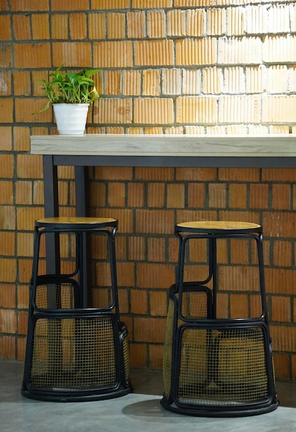 Photo two stools sit next to a bar with a plant on the top.