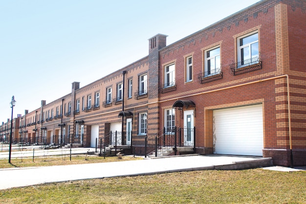 Photo two-storey residential building with separate entrances to the apartments and individual garages. townhouse. gasified. built from red, yellow and brown bricks. copy space.